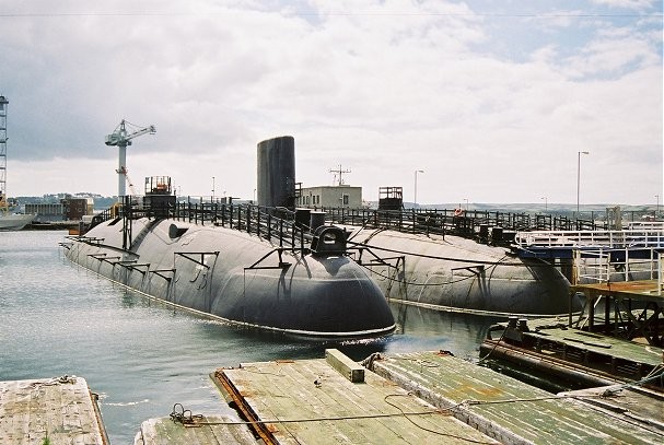 HMS Conqueror na základně, plavidlo napravo.