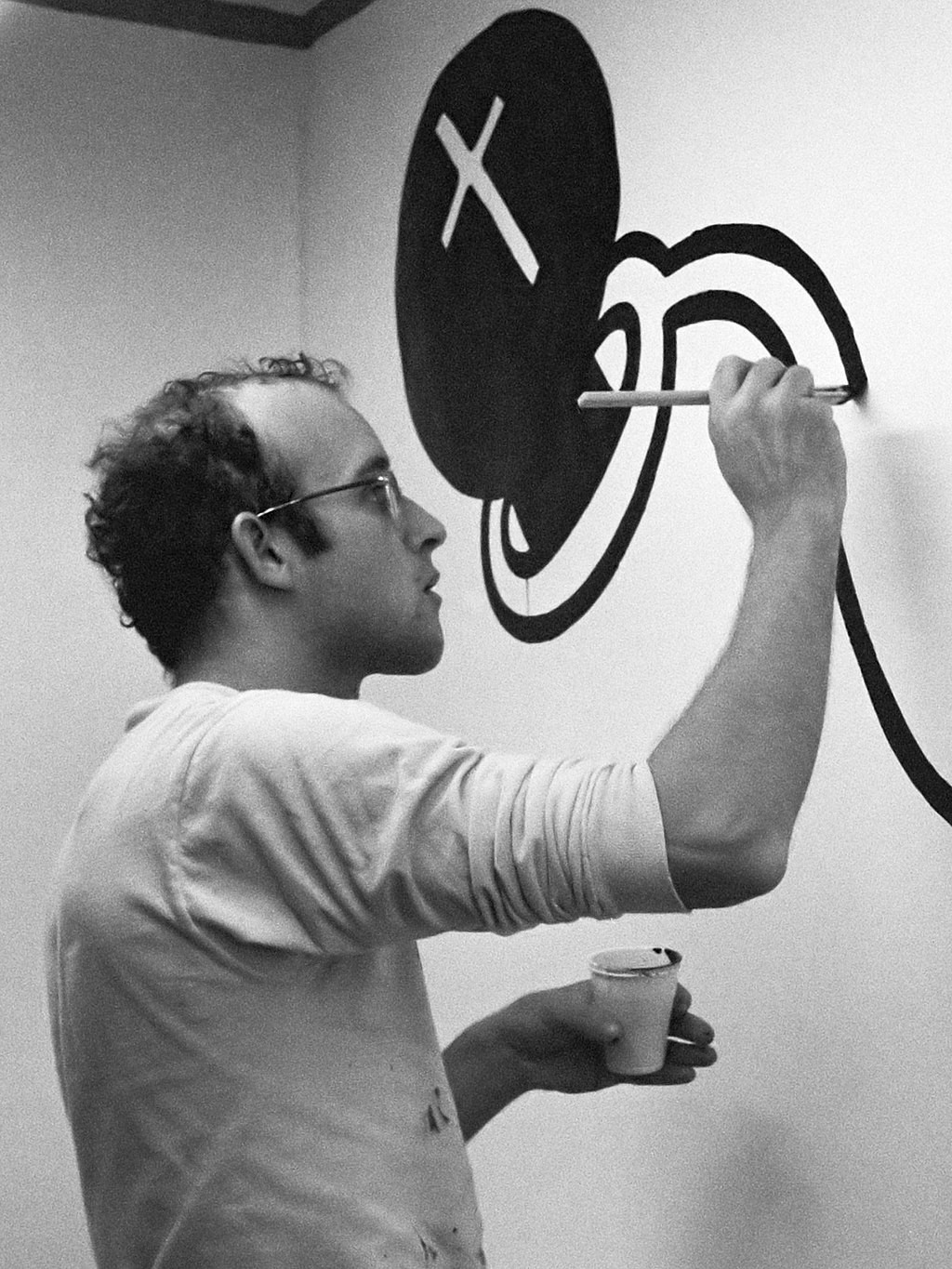 Keith Haring během malování na zeď v galerii v Amsterdamu
